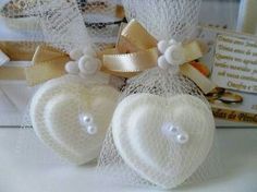 two white heart shaped soaps with bows and pearls on the top, sitting next to each other