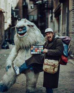 a man with a big furry animal costume on holding a rubix cube in one hand and a backpack in the other