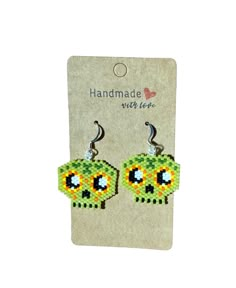 a pair of green and yellow beaded skull earrings on a white card with a tag