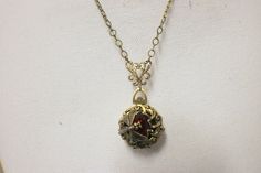 "Siam red crystal four photo locket pendant with bronze finish. Locket features a layer of bronze filigree with a s Siam red crystal set in a heart bezel the center of the locket. Wrapped around the crystal is a delicate bronze dragon fly. Locket is 1\" in diameter and hangs from a bronze filigree connector with a bronze plated chain. The chain fastens with a lobster clasp. Total pendant drop length including filigree connector is 2\" and is pictured with a 22\" chain. Please choose your chain l Red Locket Necklace For Jewelry Making, Red Locket Necklace With Round Pendant, Red Locket Necklace For Formal Occasions, Red Locket Pendant Jewelry, Red Locket Jewelry With Round Pendant, Red Round Locket Jewelry, Red Medallion Locket Necklace, Red Vintage Copper Jewelry, Vintage Red Copper Jewelry