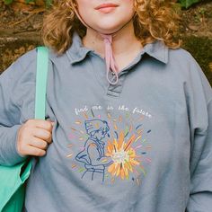 a woman with curly hair wearing a blue shirt and holding a green bag in her right hand