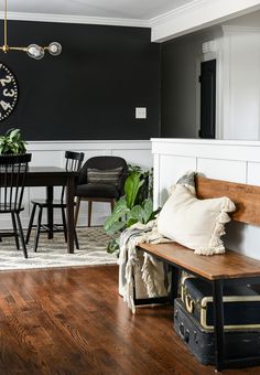 a dining room table and chairs with a clock on the wall above them, along with an old suitcase