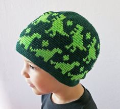 a young boy wearing a green and black knitted beanie with crosses on it