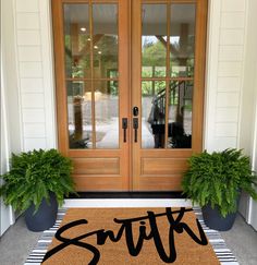 a door mat with the word sith on it and two potted plants next to it