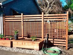 a wooden fence next to a house with plants growing in the planter boxes on it