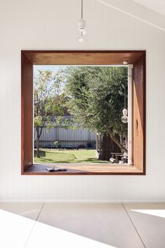 an open window in a white room with a view of the yard and trees outside