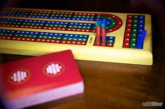 a wooden board game sitting on top of a table next to a red card holder