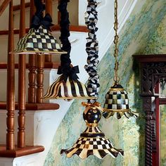 three chandeliers hanging from the ceiling in front of a stair case with blue and white wallpaper