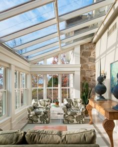 a living room filled with lots of furniture and windows covered in glass roof coverings