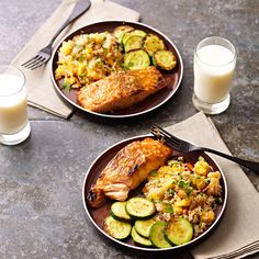 two plates filled with food next to glasses of milk