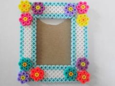 a small beaded frame with flowers on the front and bottom, sitting on a white surface