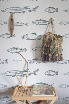 a wall with fish on it next to a wooden table and two hooks hanging from the wall