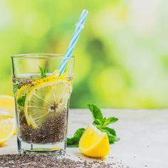 a glass filled with liquid next to lemons and mint