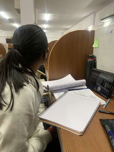 a woman sitting at a desk writing on a notebook