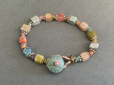 This is an especially pretty pastel agate beaded bracelet. It is made with agates that are pastel colors including blue, green, pink, beige,and coral. There are small rondel beads in between the square beads. The  pastel bracelet has silver spaces and a turquoise button and beaded loop closure. You will choose to wear this special pastel bracelet often because the  soft colors are so appealing and is the perfect accessory for many occasions.  7 1/2" long Multicolor Crystal Bracelet With Spacer Beads For Healing, Multicolor Natural Stones Beaded Bracelets For Jewelry Making, Pastel Beaded Bracelets With Colorful Round Beads, Multicolor Stretch Bracelet With Round Natural Stones, Multicolor Stretch Bracelet With Natural Stones In Round Beads, Multicolor Gemstone Bead Bracelets, Multicolor Gemstone Beads Bracelet, Handmade Bohemian Beaded Bracelets In Pastel, Handmade Bohemian Pastel Beaded Bracelets