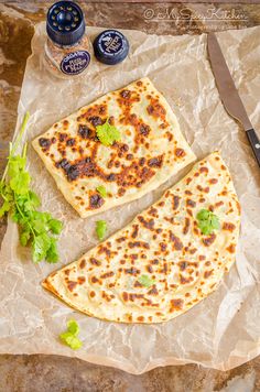 two pieces of flat bread sitting on top of a piece of wax paper next to a knife