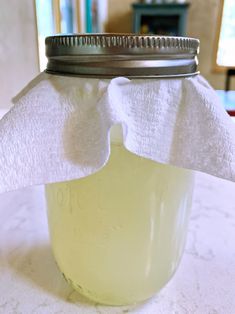 a mason jar filled with liquid sitting on top of a white tablecloth covered table