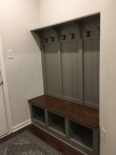 an empty room with some benches and coat racks on the wall next to a door