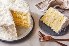 two slices of coconut cake on plates with one slice cut out and the other half eaten