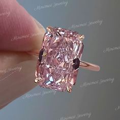 a pink diamond is being held up by someone's hand with the ring on it