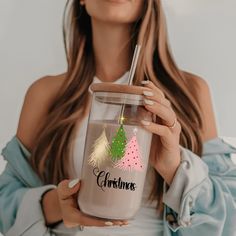 a woman holding a tumbler cup with christmas trees on it