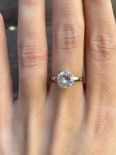 a woman's hand with a diamond ring on top of her finger, showing the center stone