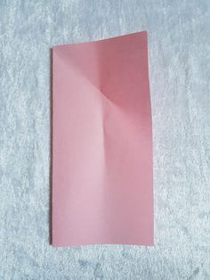 a piece of pink paper sitting on top of a white sheet of paper with one corner missing