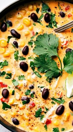 a bowl filled with black beans, corn and cilantro garnished with lime