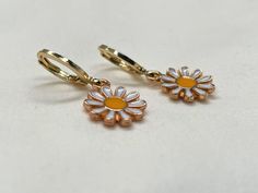 18K Gold-Filled Daisy Earrings Add a touch of playful elegance to your jewelry collection with these charming 18K gold-filled daisy earrings. Available in a huggie or ball post style, these earrings feature delicate daisy charms and add a cheerful summer vibe to any outfit. The secure huggie or ball post design ensures comfort and ease of wear, making them ideal for everyday use or special occasions. Cute Gold Flower-shaped Earrings, Cute Gold Flower Charm Earrings, Hypoallergenic Yellow Gold Drop Flower Earrings, Gold Daisy Earrings With Flower Charm, Gold Daisy Flower Earrings As Gift, Handmade Gold Daisy Earrings, Cute Gold Flower-shaped Jewelry, Cute Gold Huggie Earrings As Gift, Daisy Charm