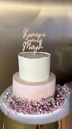 a three tiered cake with pink and white frosting on a gold plated stand