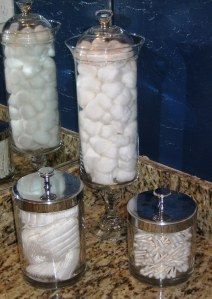 three glass jars filled with marshmallows sit on a marble countertop in front of a mirror