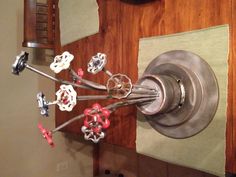 a vase filled with metal flowers on top of a wooden table next to a green place mat