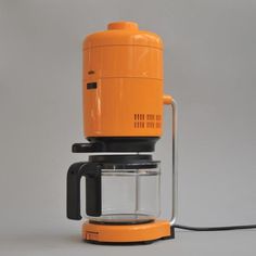 an orange coffee maker sitting on top of a table