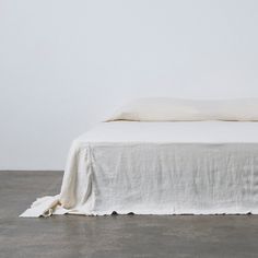 an unmade bed with white sheets and pillows