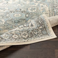 an area rug on the floor with wooden floors and dark brown wood in the background