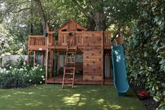 a wooden play set with a slide and climbing frame in the grass next to trees