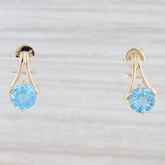 Gem: Natural Topaz - 2.10 Total Carats, Checkerboard Round Brilliant Cut, Light Blue Color, Routinely Enhanced Metal: 14k Yellow Gold Weight: 2.4 Grams Stamps: 14k, 585 Closure: Stick Posts & Butterfly Backs Measurements: 14.5 x 7.9 mm Yellow Gold Earrings With Blue Topaz And Gemstone Accents, Formal Topaz Earrings With Prong Setting, Anniversary Yellow Gold Earrings With Blue Topaz, Anniversary Yellow Gold Blue Topaz Earrings, Formal Round Topaz Earrings, Classic Yellow Gold Blue Topaz Earrings, Classic Blue Topaz Yellow Gold Earrings, Blue Topaz Earrings For Anniversary, Mens Custom Jewelry