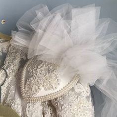 wedding dress with white lace and tulle on display in front of blue wall ornament