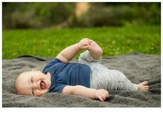 a baby laying on top of a blanket in the grass with it's mouth open