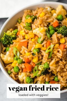 a white bowl filled with rice and veggies on top of a gray table