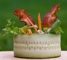 a small bowl filled with lettuce, carrots and bacon