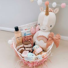 a stuffed animal sitting in a basket filled with baby goods and gifts for the little ones