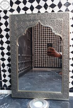 a person taking a selfie in front of a mirror with black and white tiles