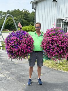 a man holding two large purple flowers in his hands