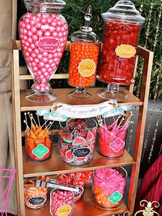 a shelf filled with lots of candy and candies on top of wooden shelves next to plants