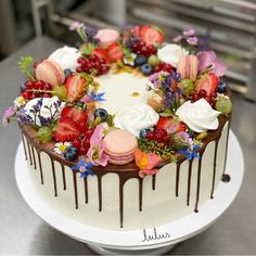 a white cake with chocolate icing and fresh fruit on top, sitting on a table