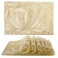 a set of gold placemats and napkins with leaves on the side,