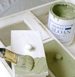 a paintbrush is being used to paint the inside of a white cabinet with green paint