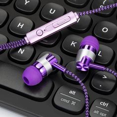 two purple earphones sitting on top of a computer keyboard with cord attached to it