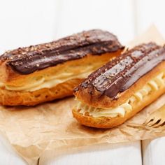 two pastries sitting on top of a piece of wax paper next to a fork